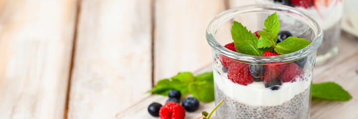 Vegan low calories chia seed pudding with fresh organic berries, plant milk, mint. Concept of dieting, detox, tasty simple super food, healthy sweet desserts. Banner. Wooden background