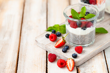 Vegan low calories chia seed pudding with fresh organic berries, plant milk, mint. Concept of dieting, detox, tasty simple super food, healthy sweet desserts. Natural antioxidant. Wooden background