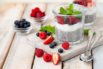 Vegan low calories chia seed pudding with fresh organic berries, plant milk, mint. Concept of dieting, detox, tasty simple super food, healthy sweet desserts. Natural antioxidant. Wooden background