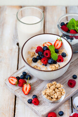 Bowl with vegan granola with fresh ripe organic berries, plant milk, mint. Concept of dieting, detox, tasty simple super food, healthy low calories breakfast. Wooden background, close up