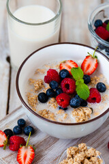 Bowl with vegan granola with fresh ripe organic berries, plant milk, mint. Concept of dieting, detox, tasty simple super food, healthy low calories breakfast. Wooden background, close up