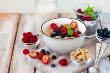 Bowl with vegan granola with fresh ripe organic berries, plant milk, mint. Concept of dieting, detox, tasty simple super food, healthy low calories breakfast. Wooden background, close up