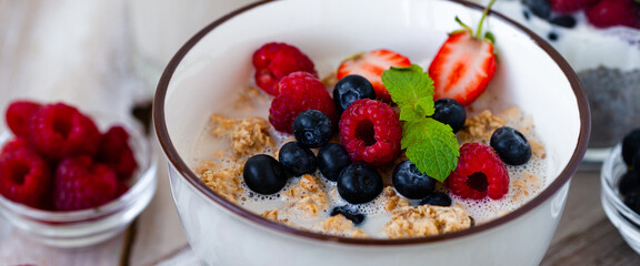 Bowl with vegan granola with fresh ripe organic berries, plant milk, mint. Concept of dieting, detox, tasty simple super food, healthy low calories breakfast. Wooden background, close up. Banner