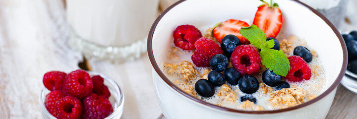 Bowl with vegan granola with fresh ripe organic berries, plant milk, mint. Concept of dieting, detox, tasty simple super food, healthy low calories breakfast. Wooden background, close up. Banner