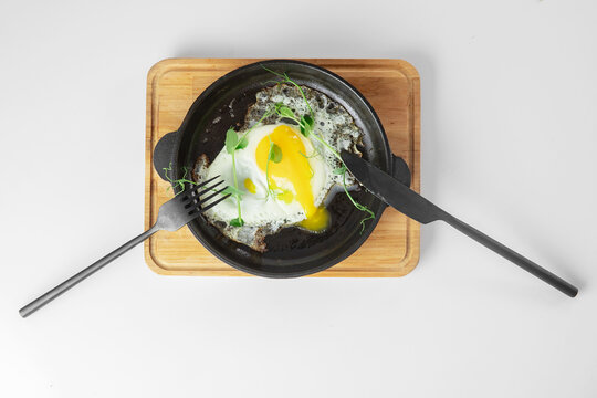Serving fried eggs in cast iron pan microgreen sprouts baby beans pea and sunflower on white background, top view
