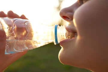 woman drinking water from a bottle face closeup summer