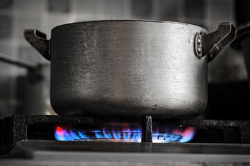 Metal brushed pot on a gas stove burner at home kitchen close up