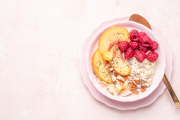 Porridge oatmeal with raspberries, peaches and nuts for breakfast. Healthy vegetarian food concept.