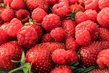 Heap of strawberries, raspberries on natural wooden background. New fresh harvest, summer, summertime, garden concept. Organic gresh natural diet eco friendly food. 