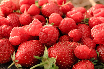 Heap of strawberries, raspberries on natural wooden background. New fresh harvest, summer, summertime, garden concept. Organic gresh natural diet eco friendly food. 