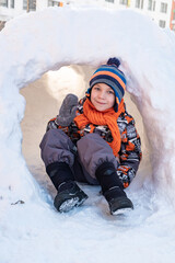 Cute boy playing in the snow castle igloo