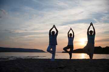 group of people practice Tai Chi Chuan  at sunset on the beach.  Chinese management skill Qi's...
