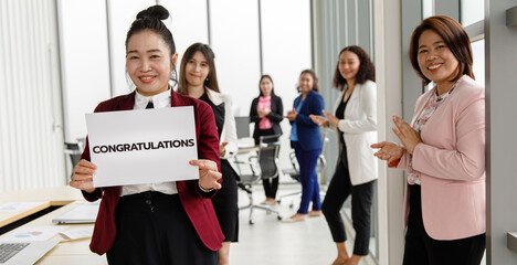 Business peopl group in business clothes set row and holding paper banner with word 'congratulations' and show to camera. Concept of greeting and appreciation for success in job or work in company