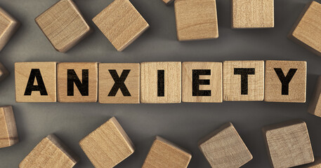 The word ANXIETY on small wooden blocks at the desk. Top view