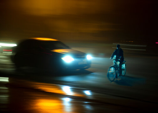 Dangerous city traffic situation with cyclist and car in the city at night