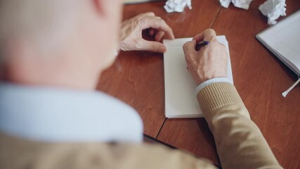 Male writer starting new book, writing down chapter one title on sheet of paper