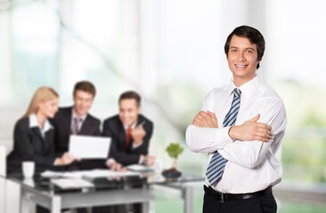 Handsome young business man standing confident in the office in front of business team