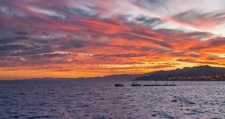 Colorful clouds during sunrise above sea and mountains