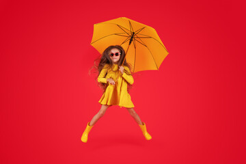 Happy emotional girl laughing with umbrella on colored red background. Autumn, spring season.