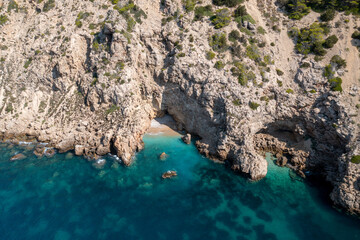 Aerial photo of the Spanish island of Ibiza showing a private secluded beach near the beach at Cala Llonga in the summer time in the Balearic Islands, Spain