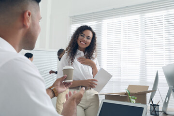 Employee offering cup of coffee to new coworker in office