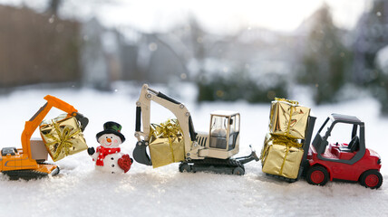 Two models of toy excavators, red forklift, souvenir snowman, gifts in gold paper stand in a row in...