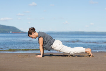 woman doing stretching and yoga on the beach. Healthy and sport lifestyle. 