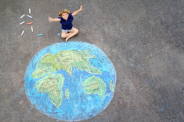 Little preschool girl with earth globe painting with colorful chalks on ground. Positive toddler...