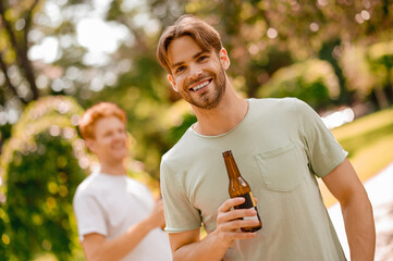 Smiling bearded guy with bottle and friend behind