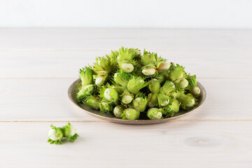 Hazelnuts in an iron plate on a wooden table.