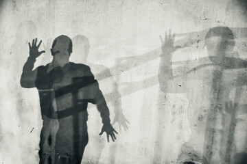 White textured wall with human shadow. Silhouette of a man with spread hands. Abstraction, horror, thriller