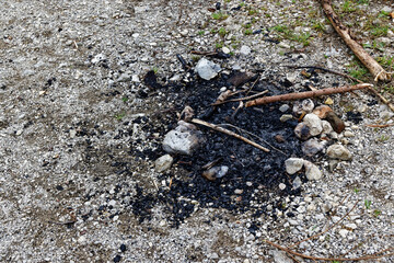 burnt charred fireplace on a gravel parking lot with stones under a cloudy sky during the day without people, a picnic with the family on the weekend pleases everyone