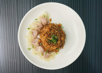 stir fried dry wanton noodle mee with meat dumpling in plate on dark grey wood table asian dim sum halal food restaurant cuisine banquet menu for cafe