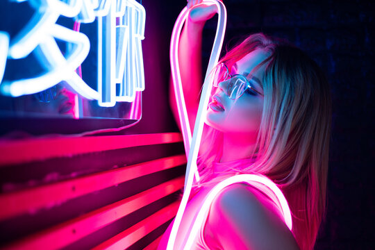Blonde girl with glass in neon light at disco