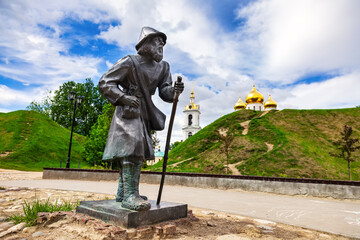 Genre sculpture "Pilgrim" against the background of the ramparts of the Dmitrov Kremlin on a sunny, warm summer day. Dmitrov, Moscow Region, Russia-July 2021