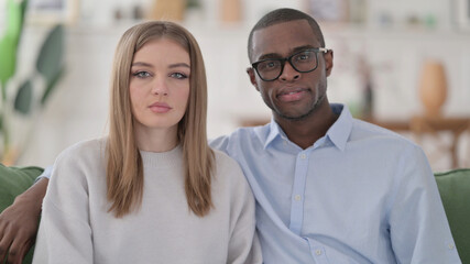 Serious Interracial Couple Looking at the Camera, Home