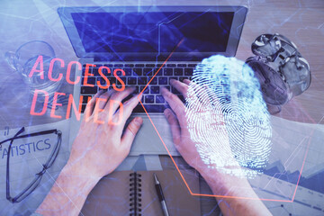 Double exposure of man's hands typing over computer keyboard and finger print hologram drawing. Top view. Personal security concept.