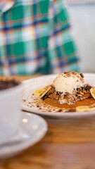 boy in green shirt eating pancake with a scoop of ice cream and banana