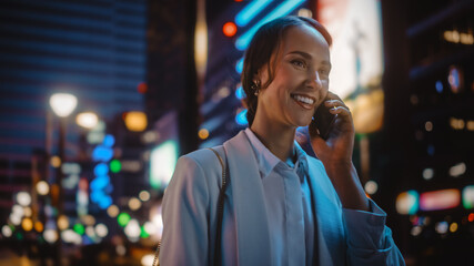 Beautiful Young Woman Talking on Smartphone Walking Through Night City Street Full of Neon Light....