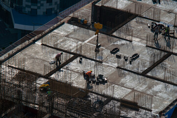 Top view of builders working with materials during construction of a skyscraper in the rays of sunlight on a summer morning