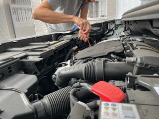 40-year-old man tightening a screw with a screwdriver inside the engine of a car with the hood open