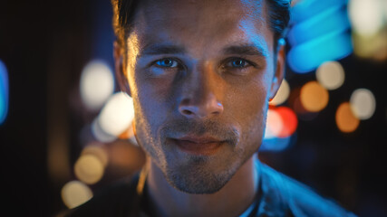Portrait of Handsome Blonde Man Smiling and Looking at Camera, Standing in Night City with Bokeh...