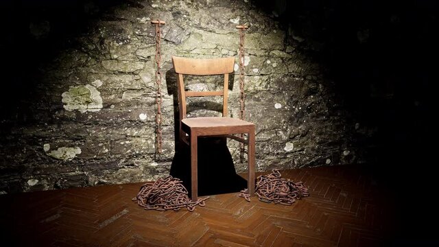 A spotlight shining down on an old wooden torture chair with rusty chains on the wall and floor.