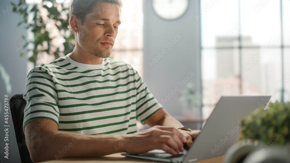 Poster portrait of handsome white man doing remote online work on laptop computer while sitting at his desk