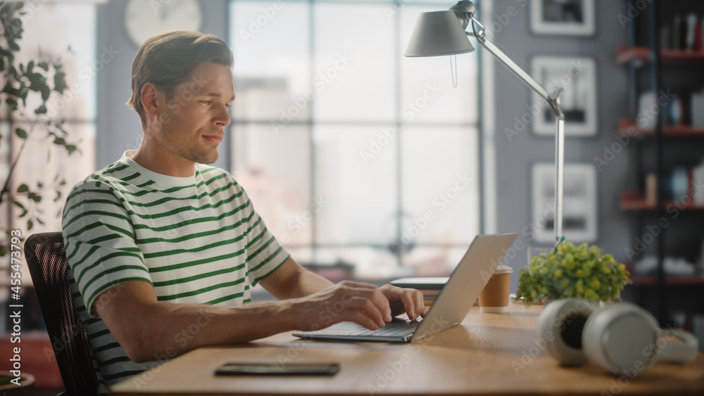 Poster portrait of handsome white man doing remote online work on laptop computer while sitting at his desk