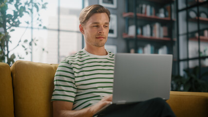 Portrait of a Man Using Laptop at Home Office, Does Remote Work. Handsome Male Sitting on Sofa Works On Computer, Brainstorms Project, does Online Shopping, Browsing Internet, Day Job.