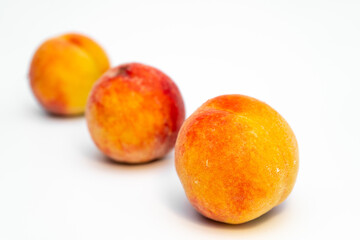 Installations of three ripe peaches on a uniform white background in different combinations. Healthy vegetarian food