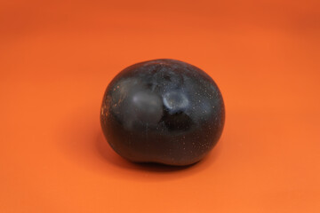 Plum close-up on a uniform orange background. Healthy vegetarian food in summer