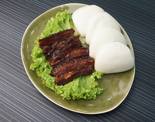 braised pork belly meat wrapped with mantou bun Chinese burger  on dark grey wood background dim sum halal menu