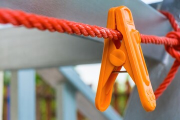 Orange clothes peg hanging on clothes line.